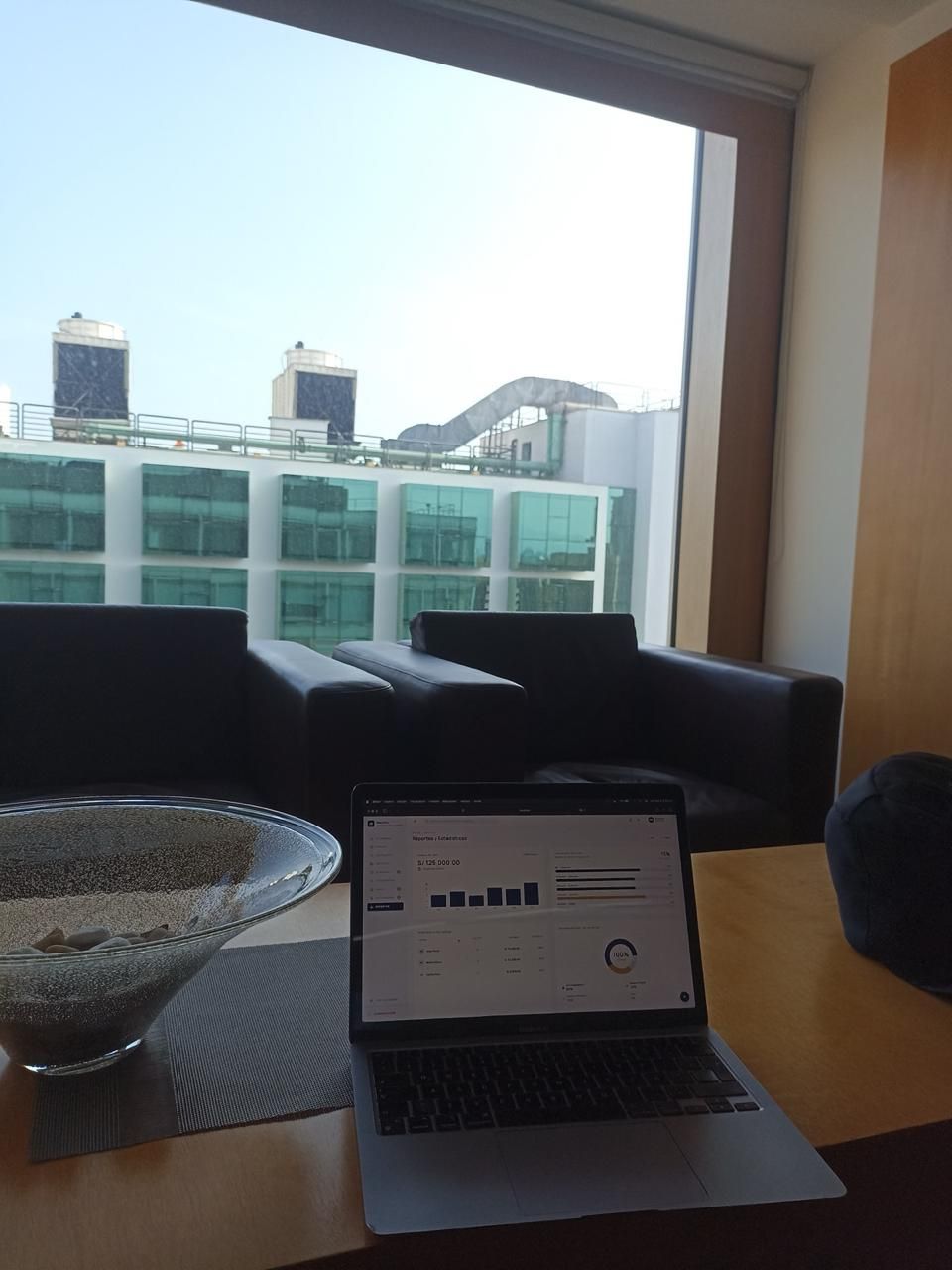 Laptop con reportes y estadísticas en una oficina con vista a la ciudad